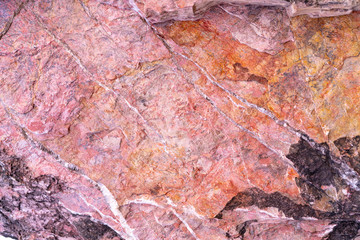 Stone texture background with unique pattern. Pink, red, black rock texture. Rock surface abstract background. Natural stone background. Purple rough stone floor. Grunge and rust rock texture.