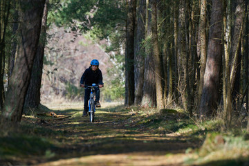 Fototapeta premium Boy with blue helmet rides a bicycle in forest