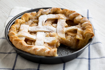 Home-baked apple pie on white wooden surface, side view. Close-up.