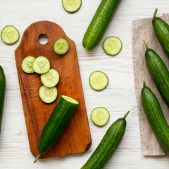 Top view, fresh raw green cucumbers over white wooden background. Flat lay, from above, overhead.