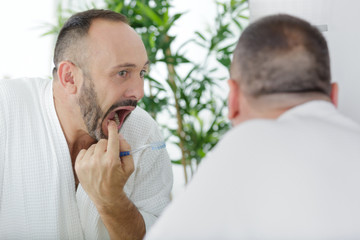 mature man checking his teeth in the mirror