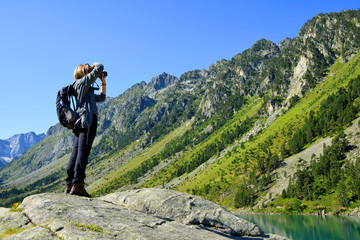 Photographer taking picture photos with DSLR camera at Gaube lake. Hautes Pyrenees, France.