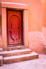 Red door with an image of Miriam's hands (Fatima's hands) close-up on a traditional Berber house. Africa Morocco Ouarzazate