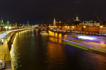 Fototapeta na wymiar Glowing trail of pleasure boat sailing along Moskva river against embankment at night