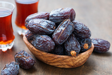 Fresh Medjool Dates in a bowl with tea on wooden background.