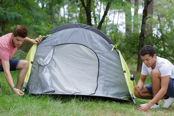 male friends setting up tent outdoors