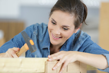 woman using a hammer works in a workshop
