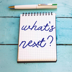 Text sign showing What'S Next question on notebook on wooden table