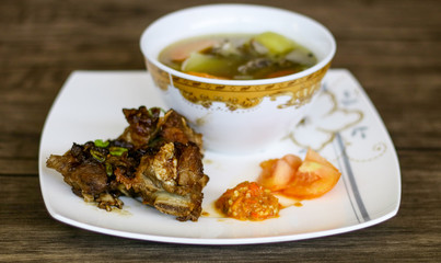 Grilled ribs, soup and chili sauce on wood background. 