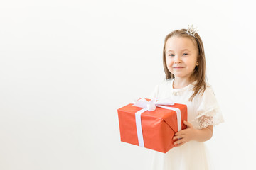 people, children and holiday concept - portrait of happy little girl holding a gift box over white background with copy space
