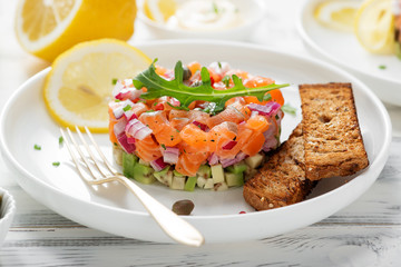 Salmon tartare with red onion, avocado, arugula and bread toast.
