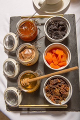 Honey, choco cream, jam, dried fruits on black stone, breakfast, top view