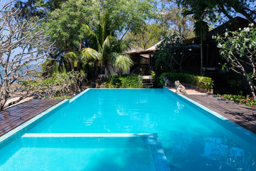Swimming pool  blue water and tropical garden with sea view background