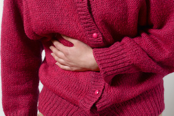 closeup photo. a woman has a pain in her stomach, and holds her hands. Concept of female medicine. Digestive problems, gynecology pregnancy, menstruation, stomach