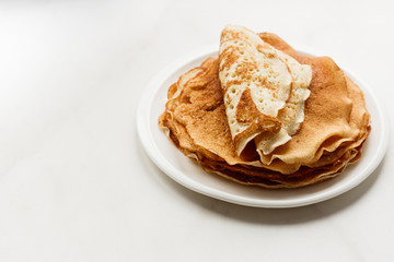 Staple of wheat golden yeast pancakes or crepes in a white plate closeup on a white background
