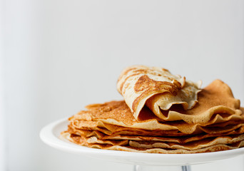 Staple of wheat golden yeast pancakes or crepes in a white plate closeup  on a white background