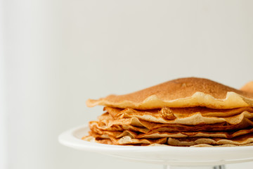 Staple of wheat golden yeast pancakes or crepes in a white plate closeup  on a white background