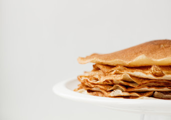 Staple of wheat golden yeast pancakes or crepes in a white plate closeup  on a white background
