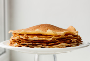 Staple of wheat golden yeast pancakes or crepes in a white plate closeup  on a white background