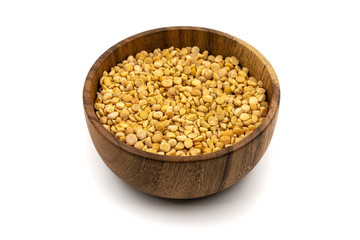 Raw yellow split peas in a wooden plate (bowl) isolated on white background