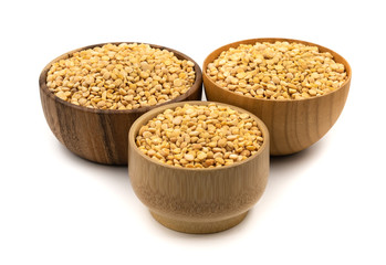 Raw yellow split peas in a wooden plate (bowl) isolated on white background