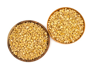 Raw yellow split peas in a wooden plate (bowl) isolated on white background, top down view