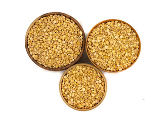 Raw yellow split peas in a wooden plate (bowl) isolated on white background, top down view