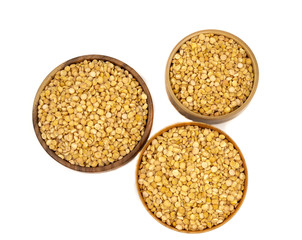 Raw yellow split peas in a wooden plate (bowl) isolated on white background, top down view