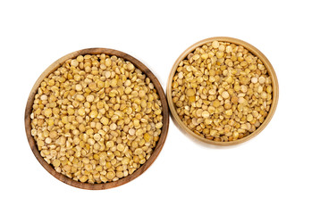 Raw yellow split peas in a wooden plate (bowl) isolated on white background, top down view