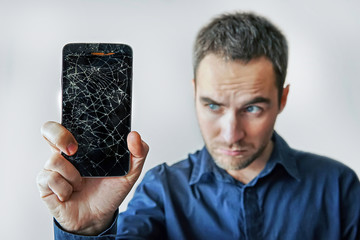 Sad man holds broken smartphone. Screen broken iphone.