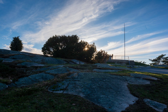 Man standing on top of ramberget hill with sunrays peeping through bush next to him