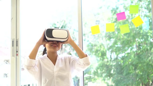 Virtual reality interaction headset by Asian Beautiful young female wearing touching air during VR box for playing game simulator future media. Technology digital Futuristic innovation device concept 
