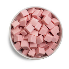 Boiled sausage cut into cubes in bowl isolated on white background. Top view