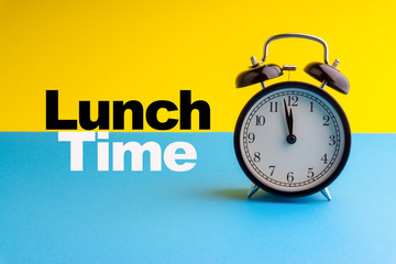 LUNCH TIME inscription written on Alarm Clock on blue yellow background. Business and motivation concept