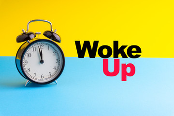 WOKE UP inscription written and Alarm Clock on blue yellow background. Business and motivation concept