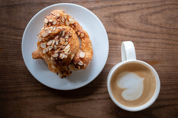 A cup of coffee with almond croissant in the morning.