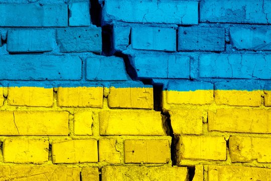 Flag Of Ukraine On The Brick Wall With Big Crack In The Middle. Destruction And Separatism Concept