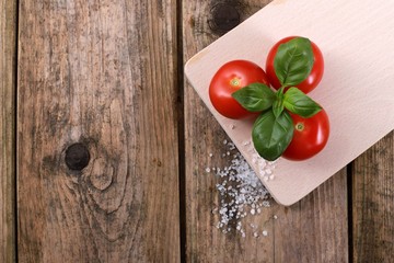  fresh tomatoes with basil and salt on a rustic wooden table - healthy breakfast 