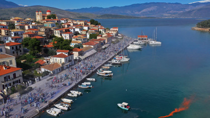 Aerial drone bird's eye view photo of people participating in traditional colourful flour war or Alevromoutzouromata part of Carnival festivities in historic port of Galaxidi, Fokida, Greece