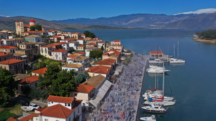 Naklejka na ściany i meble Aerial drone bird's eye view photo of people participating in traditional colourful flour war or Alevromoutzouromata part of Carnival festivities in historic port of Galaxidi, Fokida, Greece
