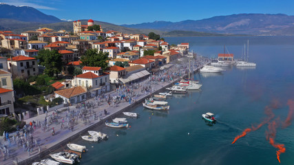 Aerial drone bird's eye view photo of people participating in traditional colourful flour war or Alevromoutzouromata part of Carnival festivities in historic port of Galaxidi, Fokida, Greece