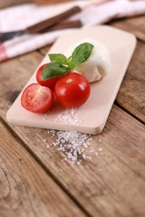 mozzarella cheese with fresh tomatoes and basil on a rustic wooden table 