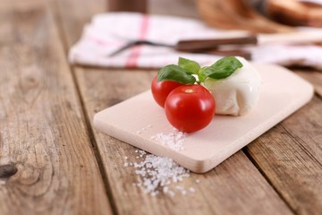 mozzarella cheese with fresh tomatoes and basil on a rustic wooden table 