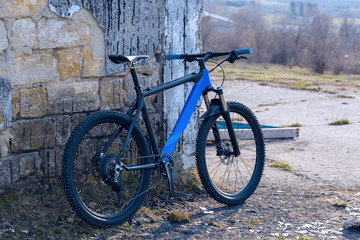 Fototapeta na wymiar A modern blue mountain bike stands at a vintage brick wall with old concrete.