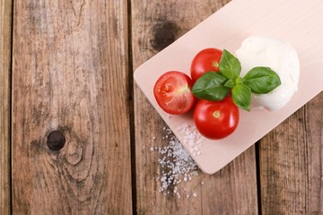 fresh tomatoes with mozzarella cheese and basil  on a rustic wooden table - healthy breakfast - top view