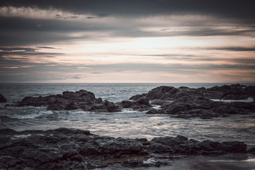 Fototapeta na wymiar Sunset in the Pacific Ocean. Waves wash the coastal stones. Costa Rica. Walk along the shore