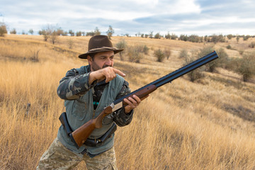Hunter with a hat and a gun in search of prey in the steppe	