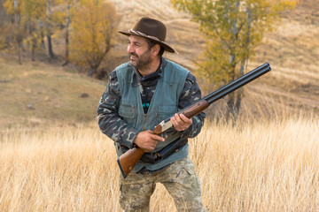 Hunter with a hat and a gun in search of prey in the steppe	