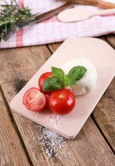 tomato mozzarella - fresh tomatoes with mozzarella cheese and basil  on a rustic wooden table