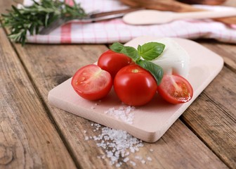 tomato mozzarella - fresh tomatoes with mozzarella cheese and basil  on a rustic wooden table